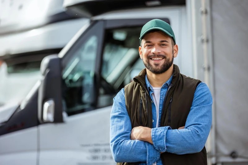 Company driver smiling in front of his truck