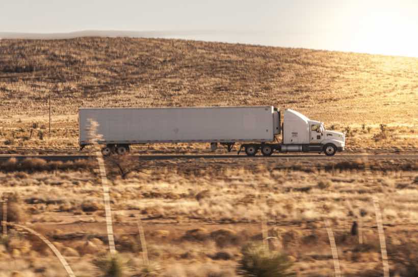 White temperature-controlled trailer running a highway lane